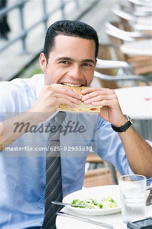 Portrait of a businessman eating a cheese sandwich
