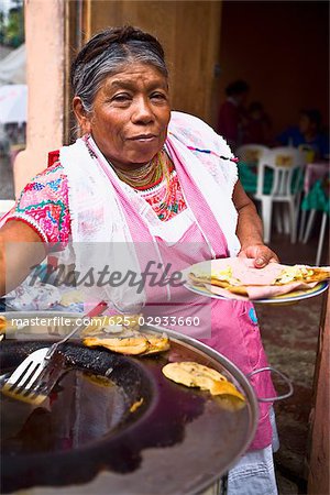 Porträt einer leitenden Frau hält eine Platte mit mexikanisches Essen, Cuetzalan, Bundesstaat Puebla, Mexiko