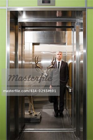 Businessman and deer standing in elevator