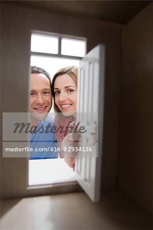 Young couple looking through door of model house