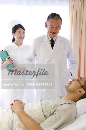 Doctor and nurse talking to patient in bed