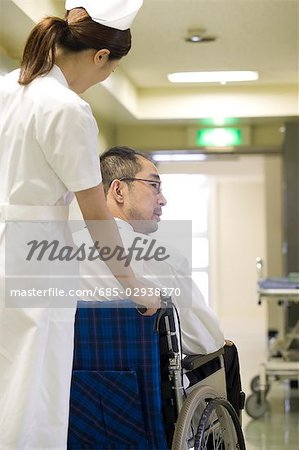 Infirmière poussant un patient en fauteuil roulant