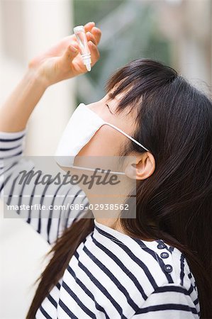 A woman applying eye drop