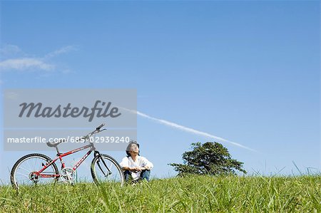 Junger Mann sitzend neben Fahrrad