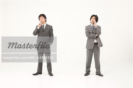 Two young businessmen talking on mobile phones