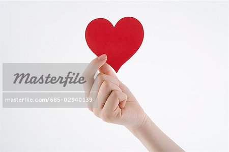 Woman's hand holding heart-shaped paper