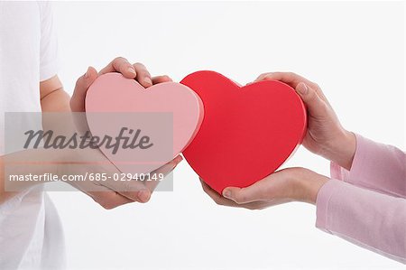 Man and woman holding heart-shaped boxes