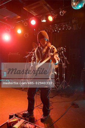 Young man playing electric guitar on stage