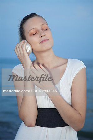 Femme sur la plage, à l'écoute de Seashell