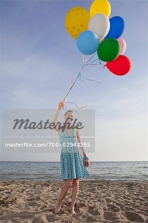 Woman on the Beach Holding a Bunch of Colourful Balloons