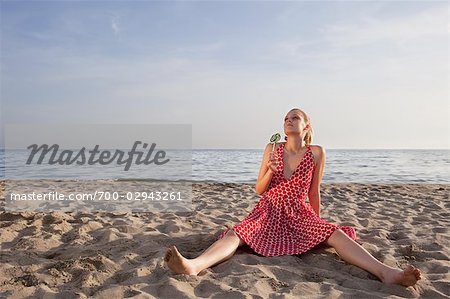 Frau mit einem Lollipop am Strand sitzen