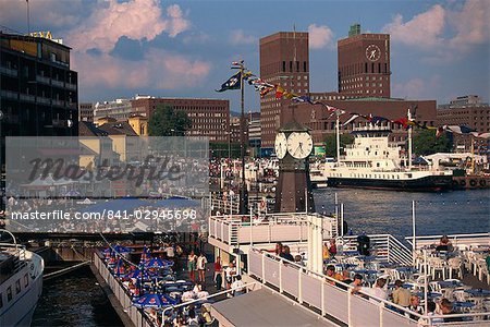 Open air restaurants around harbour, with the clock tower, and the Town Hall behind, Oslo, Norway, Scandinavia, Europe