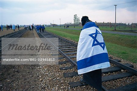 Youngster wrapped in flag walking on rail, Birkenau Concentration Camp, Oswiecim, Malopolska, Poland, Europe