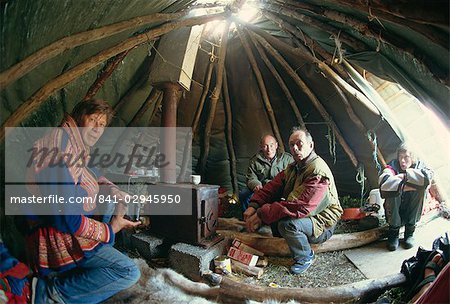 Sami man (Lapplander) à l'intérieur de la laavo (RTE-t), boire moonshine, Finnmark, Norvège, Scandinavie, Europe