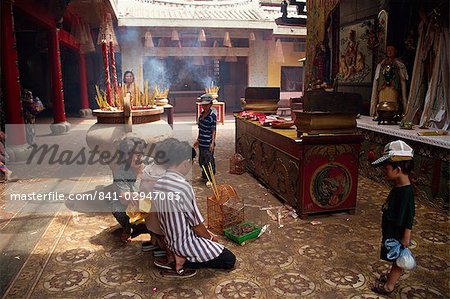 Femmes et des enfants à l'intérieur d'un temple, avec la combustion d'encens bâtons derrière, à Cholon au Vietnam, Indochine, Asie du sud-est, Asie