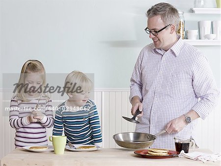father and children making breakfast
