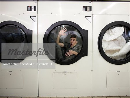 man inside a commercial clothes dryer at a laundromat