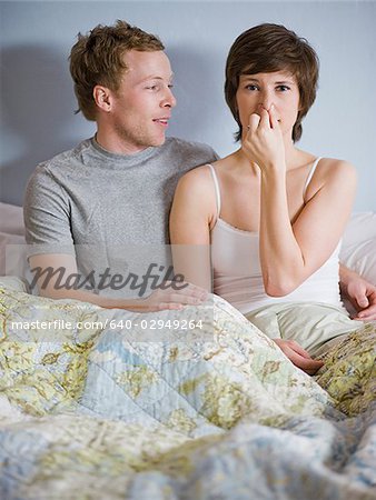 couple in bed with woman holding her nose