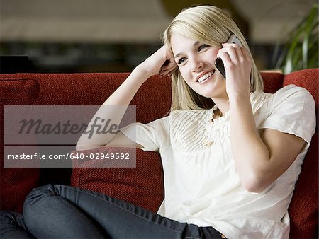 woman using her cell phone on a red sofa