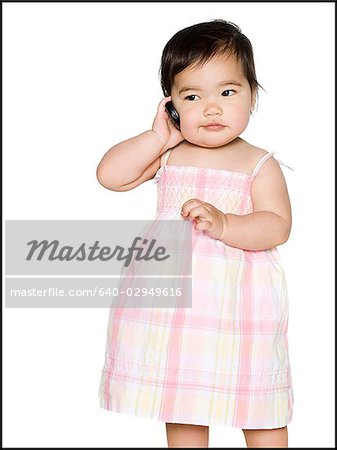 baby girl in a pink dress holding a cell phone