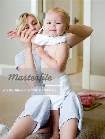 mother putting clothes on baby girl