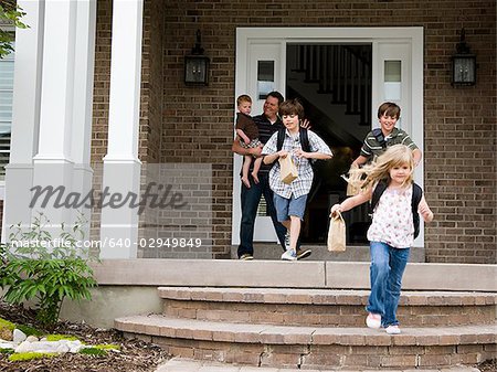 children leaving for school as father watches