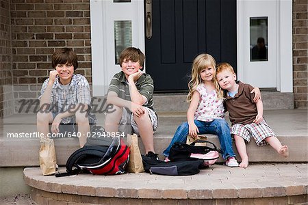 children sitting on the front step of their house