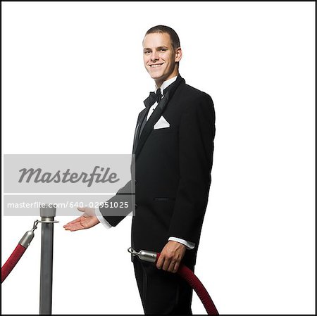 man in a tuxedo next to a velvet rope