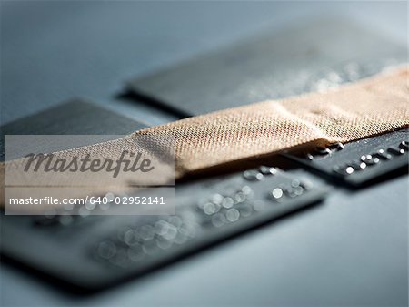 credit card cut in half with a band-aid holding it together