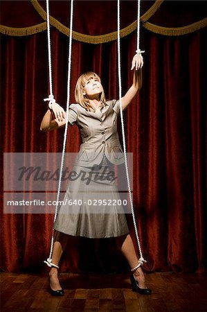 businesswoman being pulled by strings like a puppet