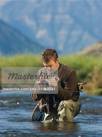 fly fisherman fishing in a mountain river