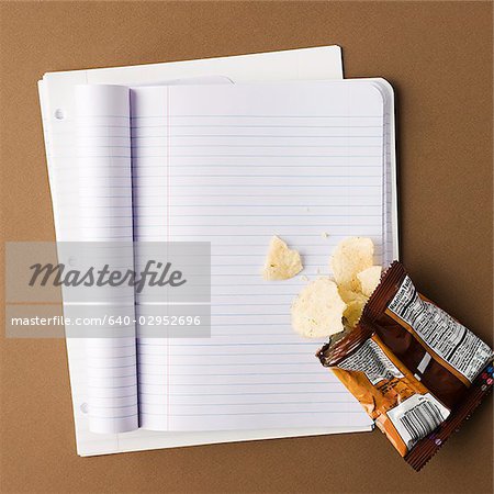 Notebook mit einer Tüte Chips auf eine leere Seite verschüttet
