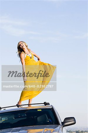 femme debout sur le toit de sa voiture sur le bord de la route