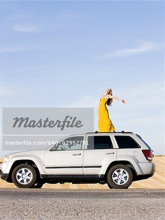 femme debout sur le toit de sa voiture sur le bord de la route