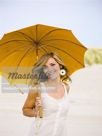 femme tenant un parasol à la plage