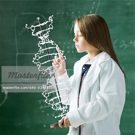 girl in a classroom with a model of a DNA double helix
