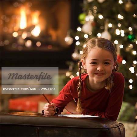 fille regardant la caméra tout en écrivant une lettre à Noël