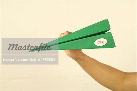 Main tenant un avion en papier vert avec étiquette CO2