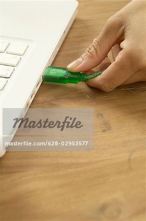 Woman plugging USB stick into laptop