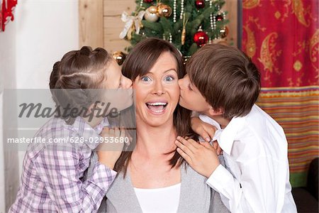 Boy and girl kissing their mother