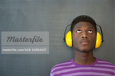 Student wearing ear protection leaning against blackboard