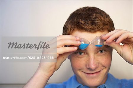 Jeune homme tenant un verre de sable en face du visage