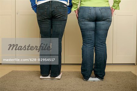 Zwei volle Figur-Frauen in Blue Jeans stehen auf der Waage (Teil von)