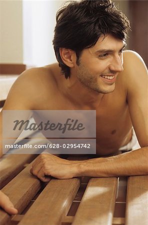 Darkhaired Man lying procumbently on a wooden Bench - Look - Allurement