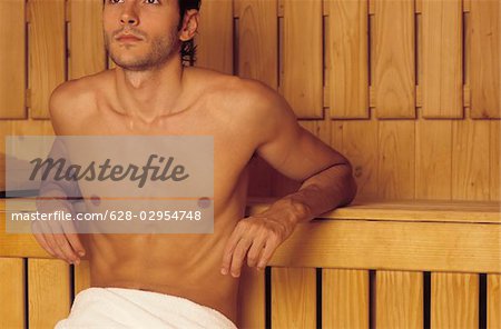 Darkhaired Man resting his Arms on a wooden Bench - Heat - Sauna - Wellness