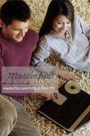 Woman lying next to a Man with Laptop on a Carpet - Communication - Technology - Living Room