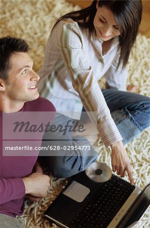 Woman lying next to a Man with Laptop on a Carpet - Communication - Technology - Living Room