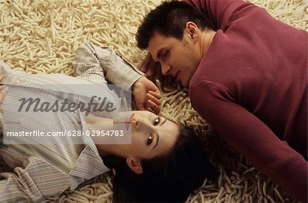 Young Man lying Head to Head with his Girlfriend on a Carpet - Relationship - Love - Home - Living Room