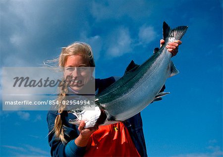 Young woman holds her caught Coho Salmon near Clarence Strait in Southeast Alaska during Summer