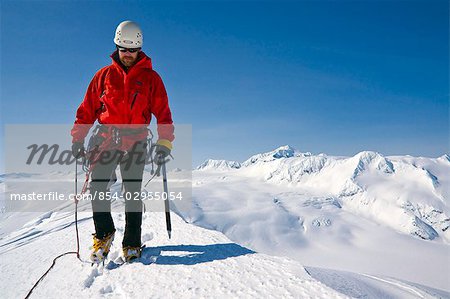 Climber on the summit of a unnamed peak above Whittier Glacier with Chugach Mountains in the background, Alaska
